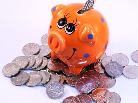 Bunch of Latvian lat coins and piggy bank on white background