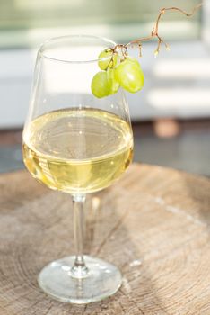 Glass of white wine with grapes on wooden surface