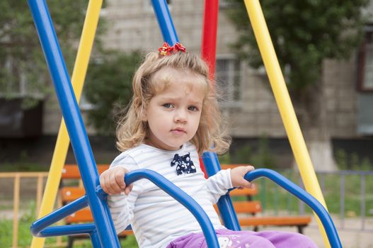 Two-year-old girl riding on a swing in the Playground. Portrait