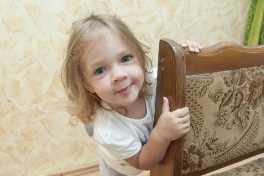 The girl in the game Peeps out of the chair and looks with a smile in the frame