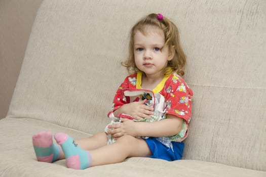  A little girl sits on the couch. To itself the girl pressed a few handkerchiefs not wanting to give them to anyone