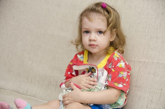  A little girl sits on the couch. To itself the girl pressed a few handkerchiefs not wanting to give them to anyone
