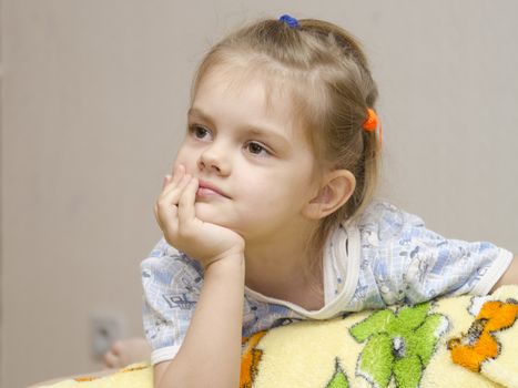Girl enthusiastically looking off to the left. Head girl at hand. The girl is watching TV. Home furnishings