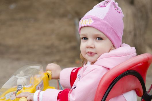 A little girl sat on the bike and turning looks in the frame. The portrait. A warm spring day