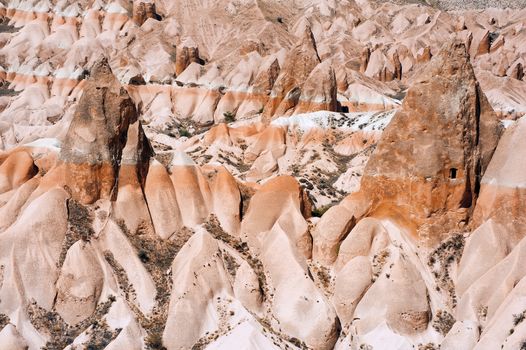 Detailed photo of vivid pink rock formations with caves from above in Cappadocia, Turkey