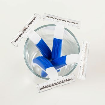 Picture of a few razors for men in a glass over a white background