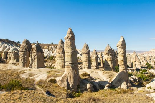 Two unrecognizable tourists watching fairy tale chimneys near Goreme, Cappadocia, Turkey