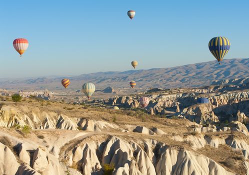 Hot air balloons flying over Cappadocia near Goreme at sunrise, Turkey