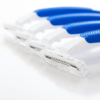 Picture of a few white and blue razors for men over a white background