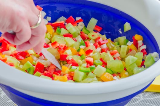 Fresh pepper salad mix of green, yellow and red peppers in a blue and white bowl.