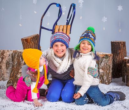 Winter Fashion. Adorable happy boy and girls in winter hat, gloves and sweater in studio.