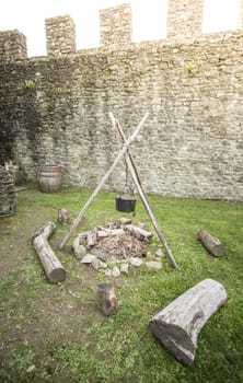 A medieval campfire with stone walls in the background