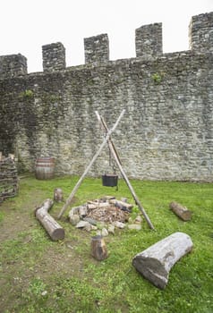 A medieval campfire with stone walls in the background
