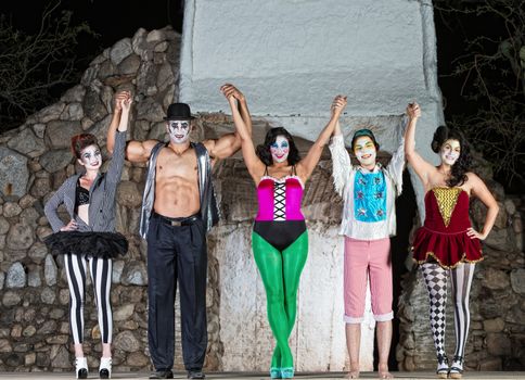 Group of happy cirque clowns holding hands