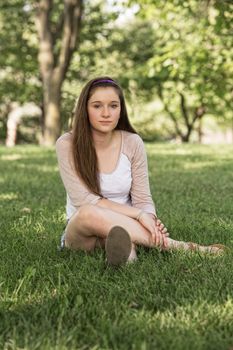 Calm teenage female sitting on grass outdoors