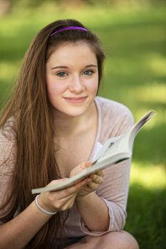 Close up of grinning female teen reading book