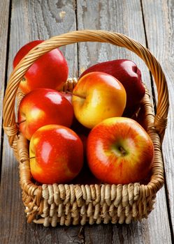 Fresh Ripe Red Prince Apples in Wicker Basket isolated on Rustic Wooden background 