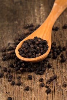 black pepper on wooden spoon and wood background