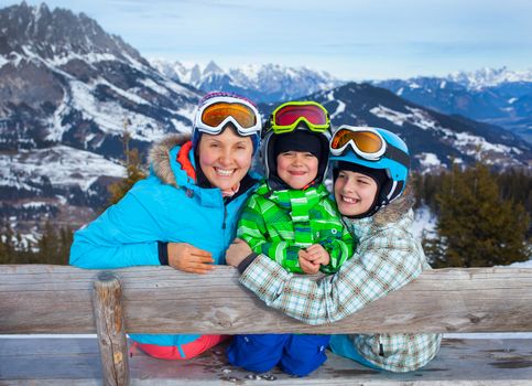 Ski, winter, snow, skiers, sun and fun - Two happy kids with mother enjoying winter vacations.