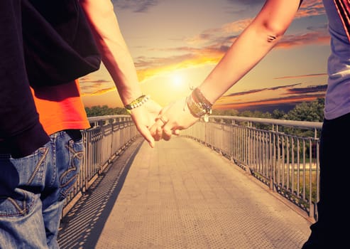 View of lovers couple holding hands on the bridge