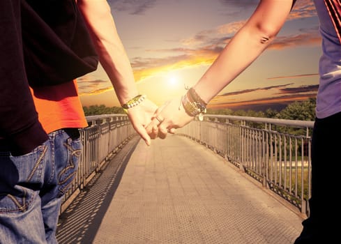 View of lovers couple holding hands on the bridge