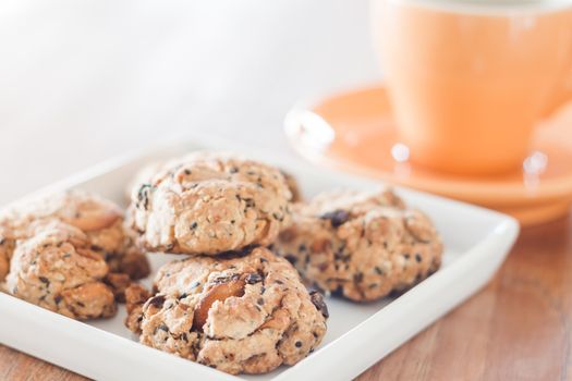 Closeup cereal cookies on white plate with coffee cup, stock photo