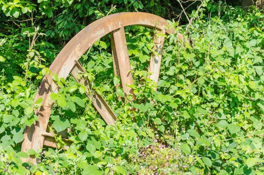 Old wheel of a coal mine conveyor system almost overgrown stuck in Waldboden.Die nature to bring everything back.