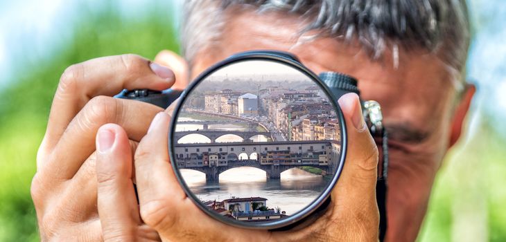 Photographer taking photo with DSLR camera at Florence cityscape. Shallow DOF