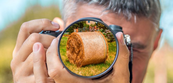 Photographer taking photo with DSLR camera at Hay Bales. Shallow DOF