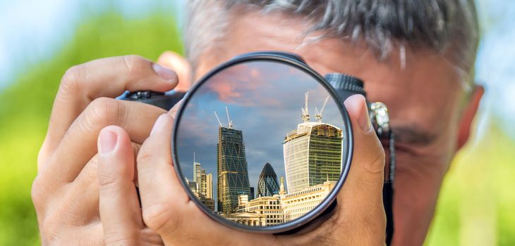 Photographer taking photo with DSLR camera at London buildings. Shallow DOF