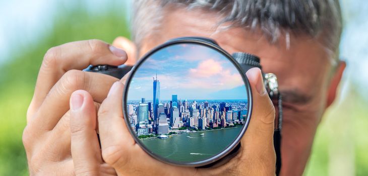 Photographer taking photo with DSLR camera at lower Manhattan buildings. Shallow DOF