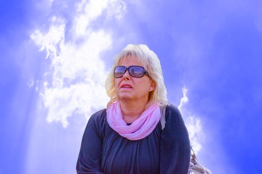 Blonde woman looking at the sky in the background storm clouds
