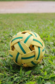The rattan ball is on the wet grassland.