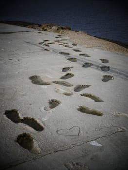  footprints on cement surface going to water abstract background.