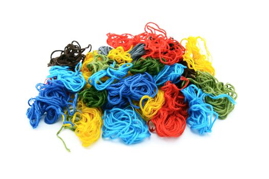 Assorted colourful embroidery threads in a heap, isolated on a white background