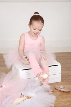 Little ballet girl trying on shoes at the ballet studio