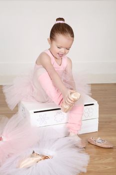 Little ballet girl trying on shoes at the ballet studio