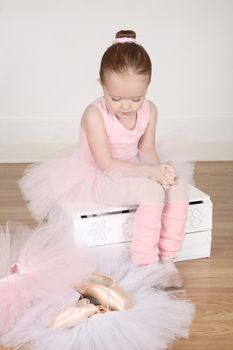 Little ballet girl trying on shoes at the ballet studio