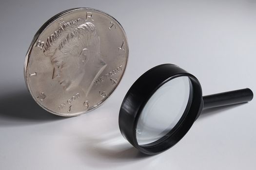 Isolated jumbo half dollar coin and magnifying glass