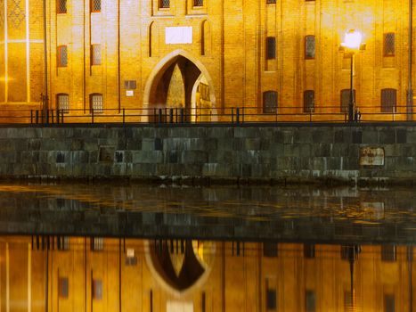 Riverbank with historical gate reflection by night, Gdansk, Poland