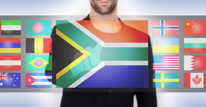 Hand pushing on a touch screen interface, choosing language or country, South Africa