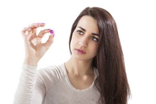 Beautiful girl holding pink pill isolated on white background. Painkiller pill.