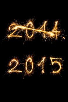 Strikethrough 2014 and 2015 digits made of sparkling light isolated on black background. Old year going, new year comming.