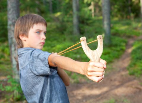 Boy aiming wooden slingshot outdoors