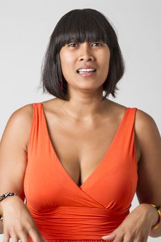 Philipino woman, wearing a low cut orange dress, with unsure expression
