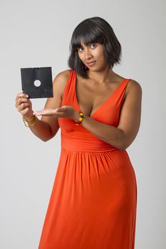 Sexy asian woman wearing a low cut orange dress, holding an old 5 in floppy disk
