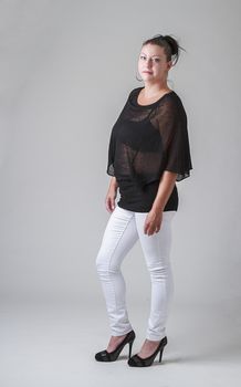 woman in her thirties, wearing a transparent shirt, against a gray background