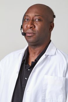 Forty year old black man, wearing a lab coat with telephone headset on his head