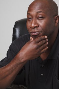 bald black man holding his chin and looking cool