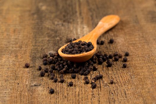 black pepper on wooden spoon and wood background